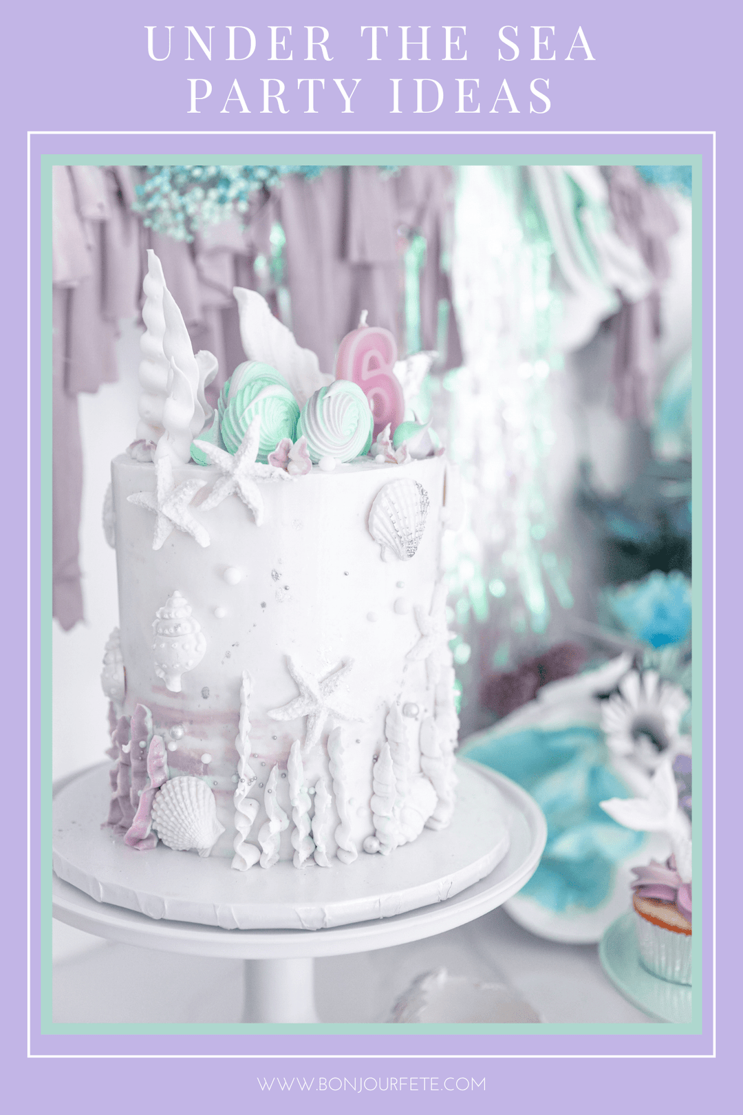 Under the sea mermaid birthday party cake with white seashells, starfish, and a number six candle on a cake stand.