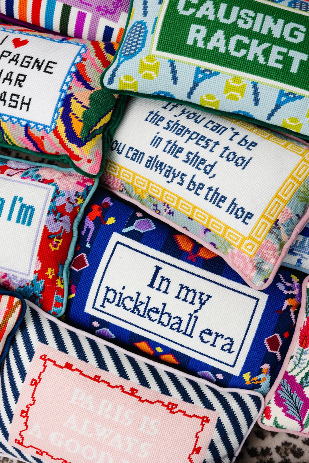 Furbish Studio needlepoint pillows with witty hand-stitched sayings, styled as sofa decor and giftable accents.