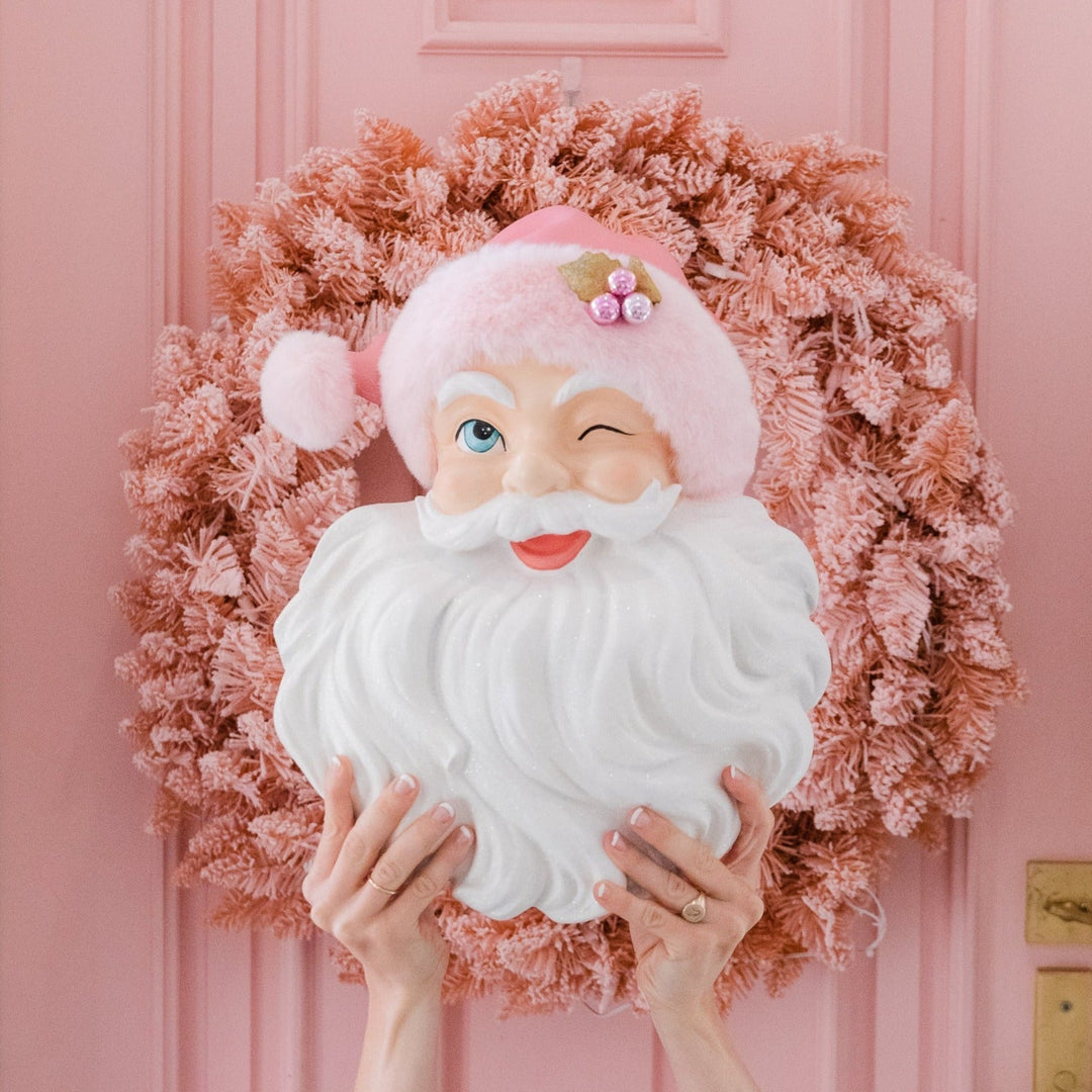 Pink santa in front of a pink wreath and cute tableware and decor for all pink holiday party themes.