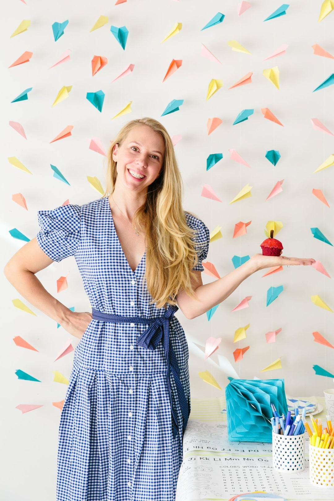 Bonjour Fete founder Rachel Huntington holding an apple cupcake, curating back to school party picks.