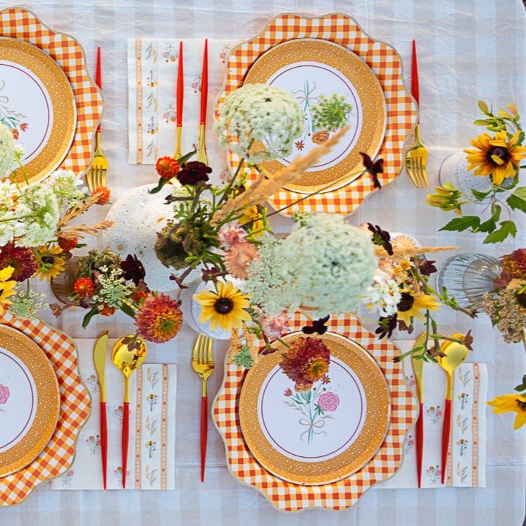 Cozy fall party table with warm-toned plates, plaid napkins, and candles styled for Thanksgiving and autumn dinners.