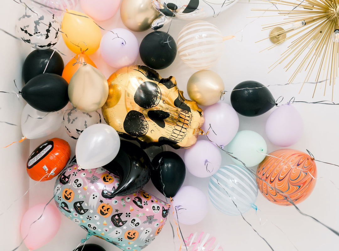 Halloween balloon display with a gold foil skull, bat-print, and pastel latex balloons for a spooky party or Halloween birthday.