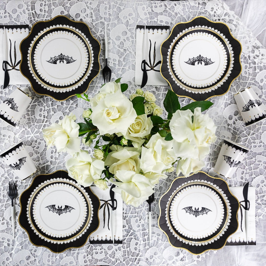 Elegant Halloween tabletop set for four with black and white place settings and white florals for a chic dinner party
