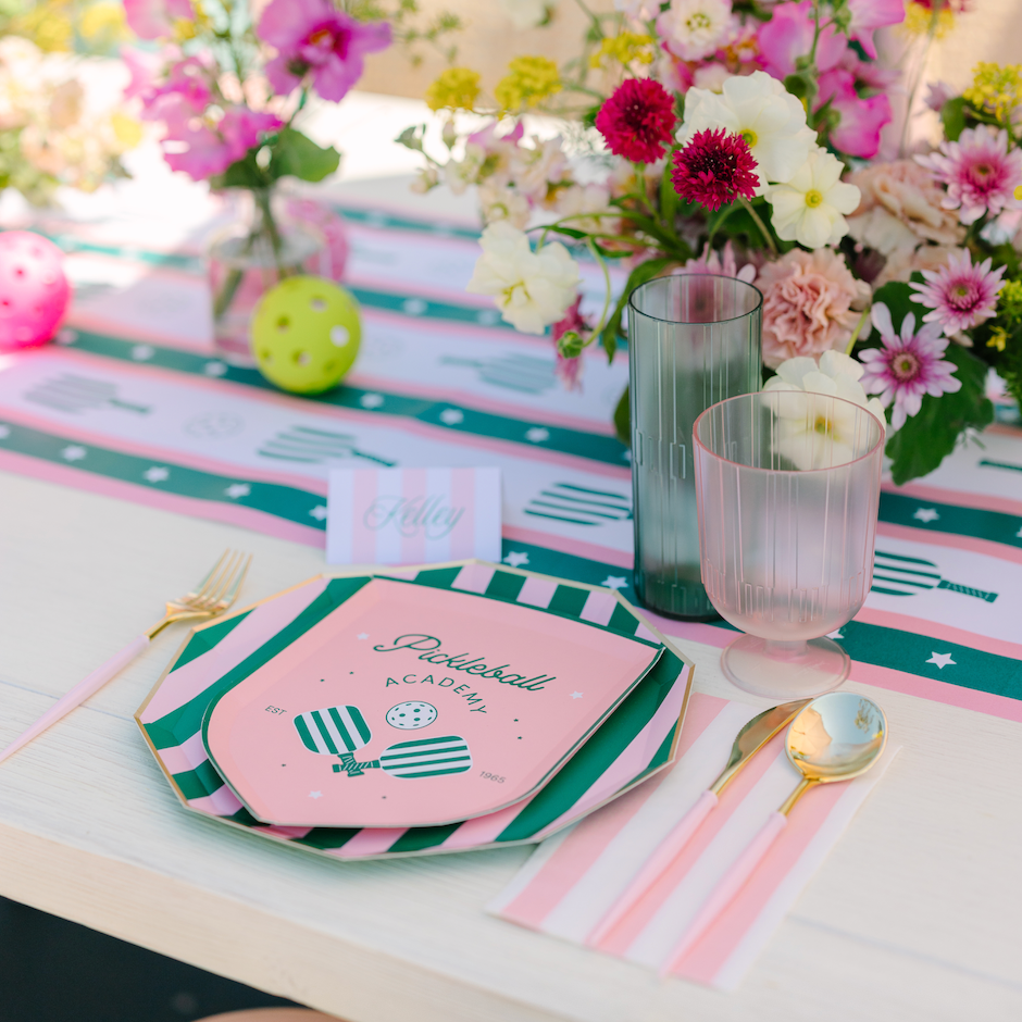 Gold and blush cutlery at a pickleball party place setting with pink and green plates