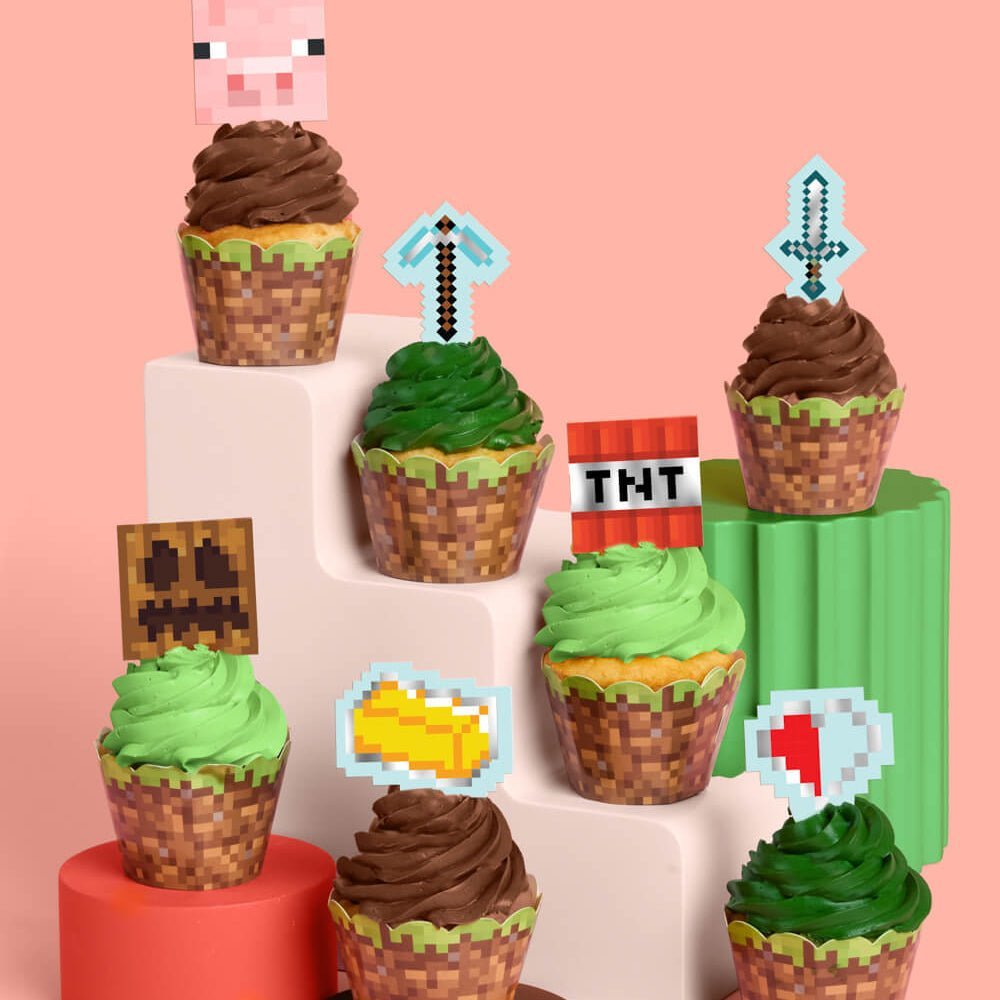 Pixel mining cupcake set by xo Fetti with grass-block wrappers and pixel toppers including a pig, torch, and gold bar