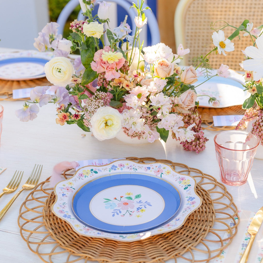 Blue floral dessert plate layered on a scalloped floral plate over a rattan charger at a spring party