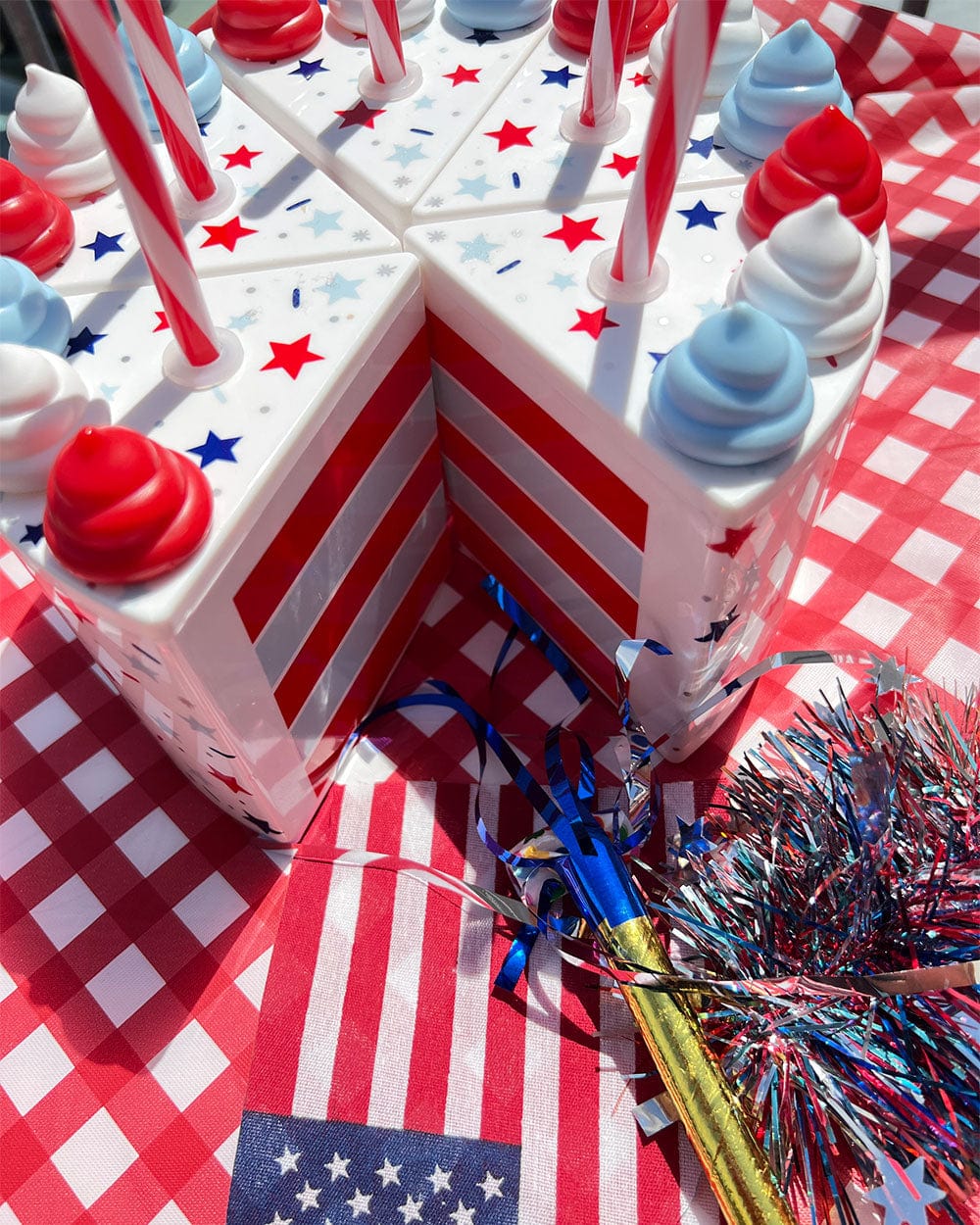 Patriotic cake slice cups arranged as a whole cake with a flag and tinsel on red gingham