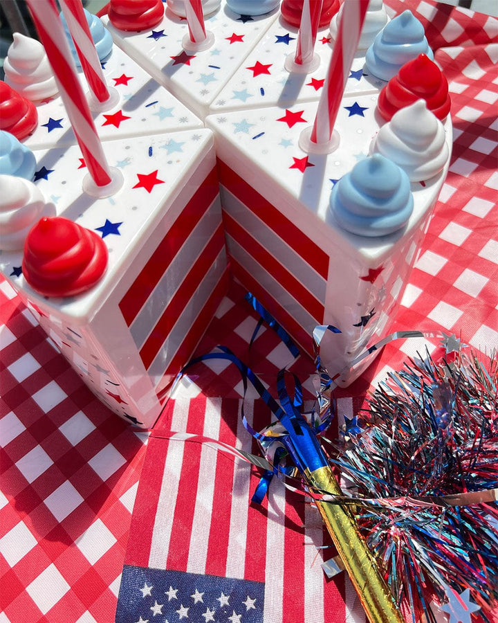Patriotic cake slice cups arranged as a whole cake with a flag and tinsel on red gingham