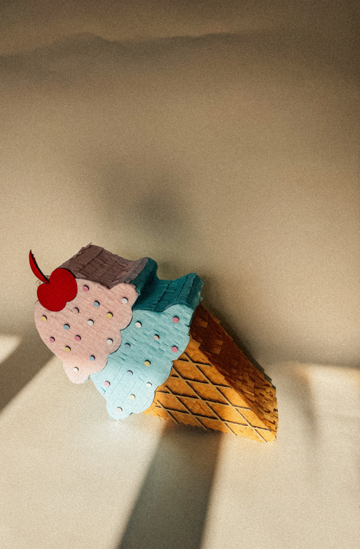 Pinata ice cream cone with colorful layers on a beige surface
