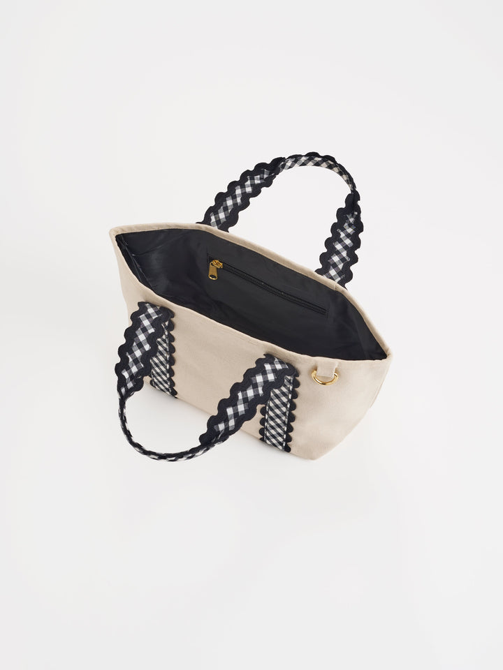 Beige handbag with black gingham handles on a white background