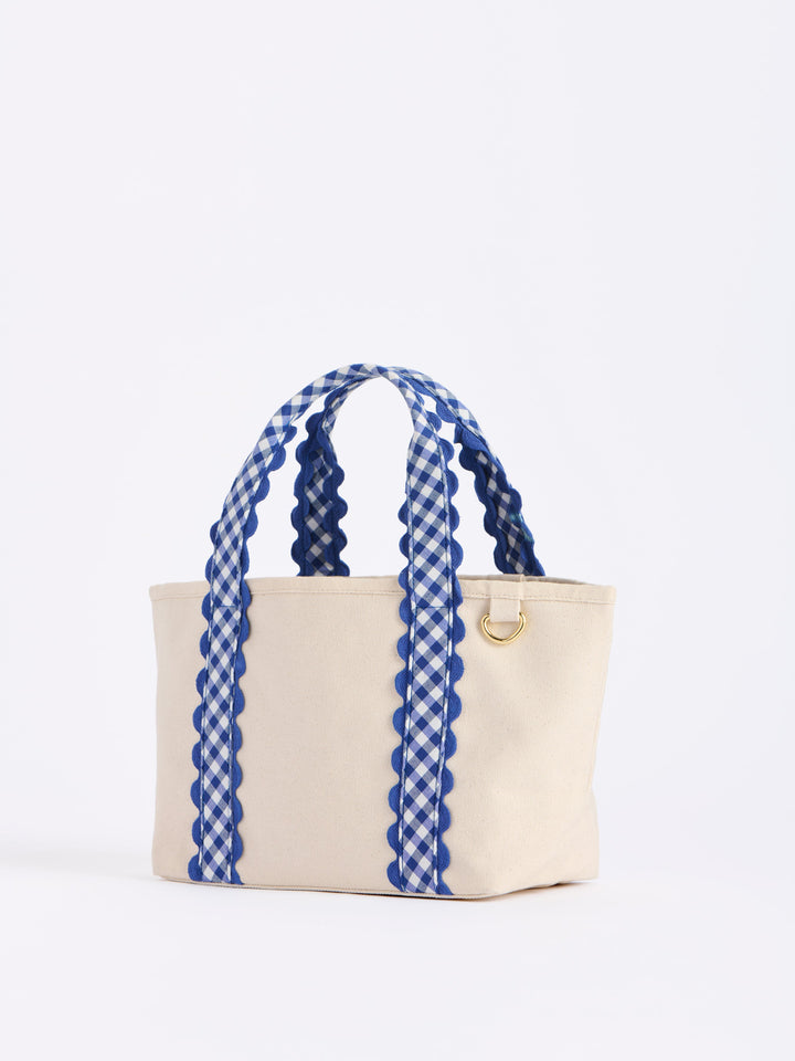 Beige tote bag with blue gingham handles on a white background
