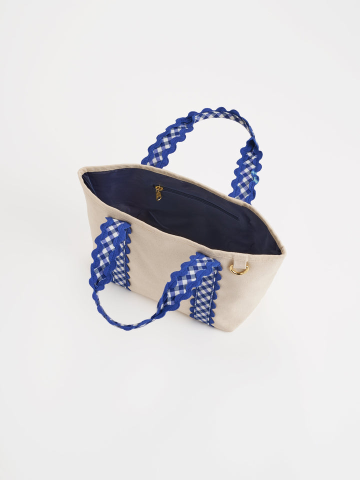 Beige tote bag with blue gingham handles on a white background