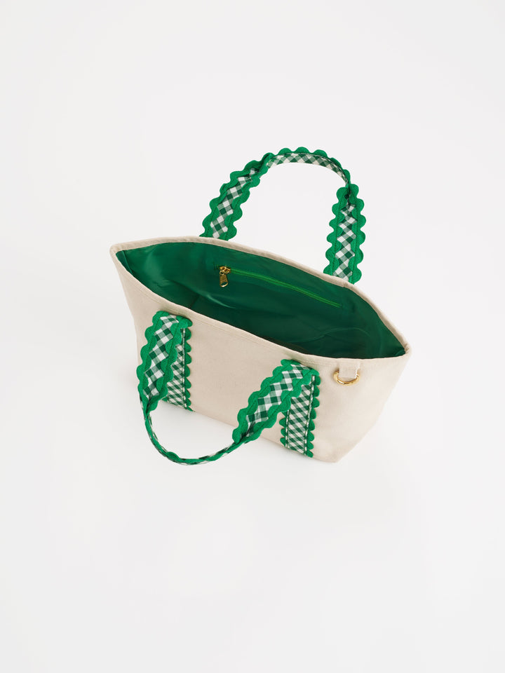 A cream canvas tote bag with vibrant green woven handles and a green interior, shown on a plain white background.