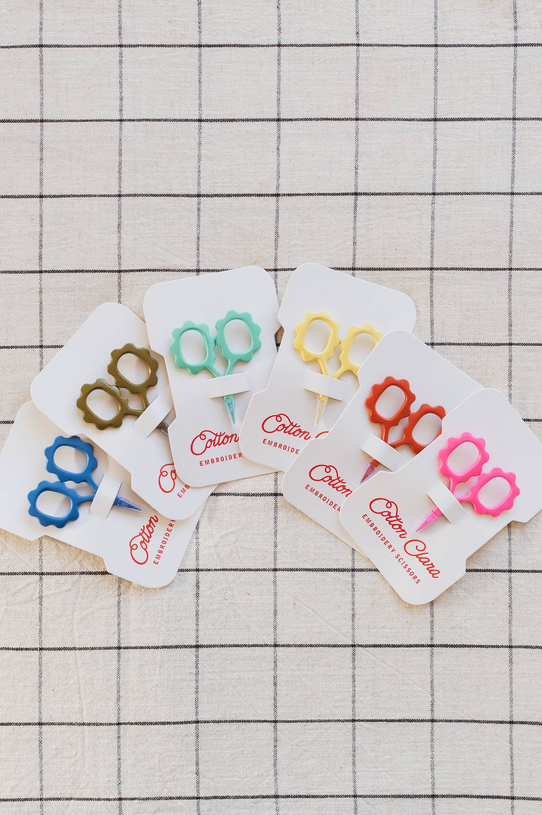 Rainbow of Cotton Clara flower embroidery scissors fanned on white grid cloth