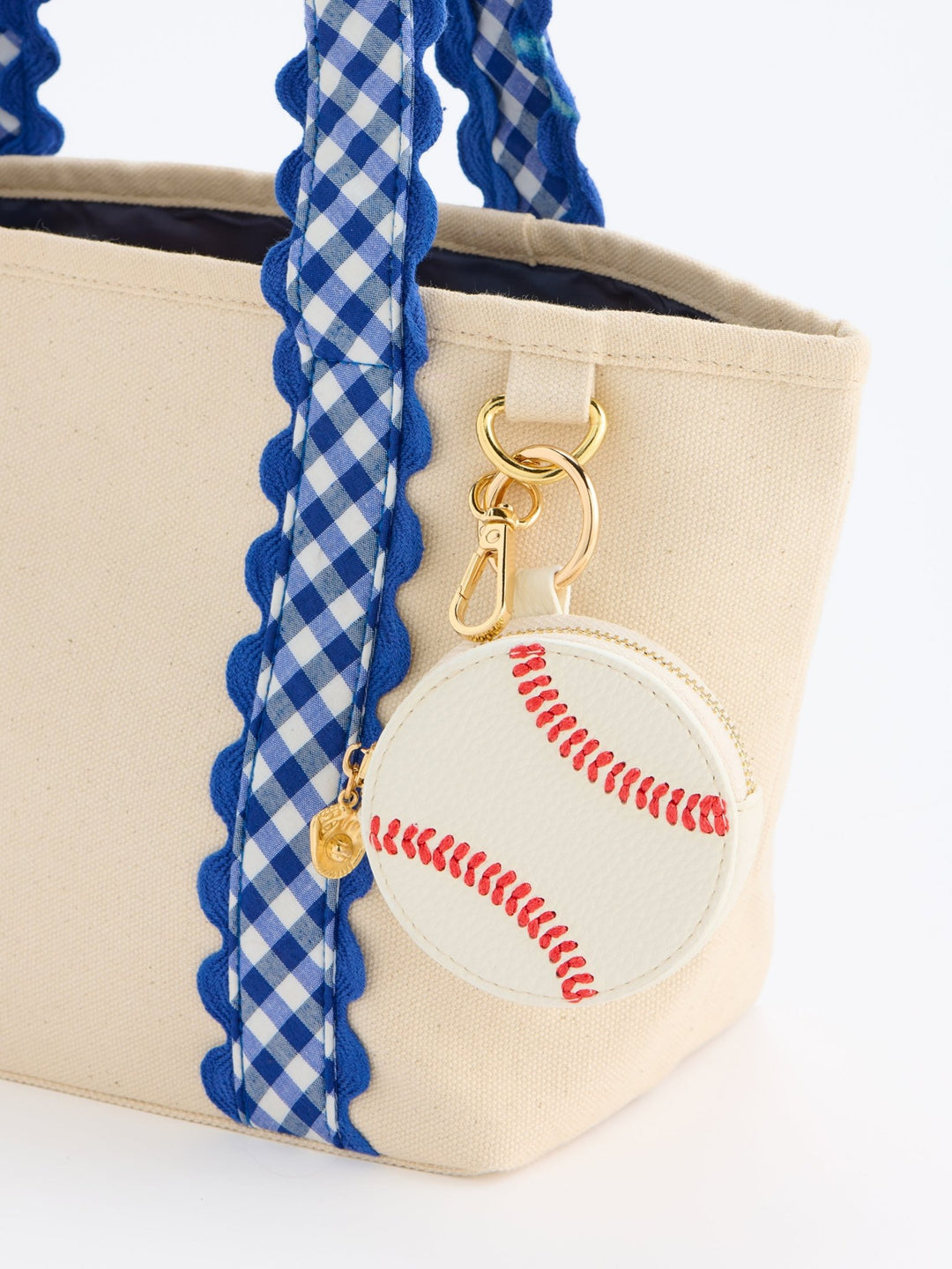 Beige canvas tote bag with blue and white gingham patterned handles, a scalloped trim, and a round baseball-themed zipper pouch with red stitching and gold hardware.