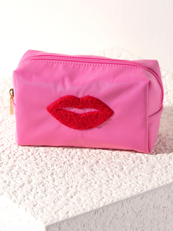 Pink pouch with red lip design on a textured surface