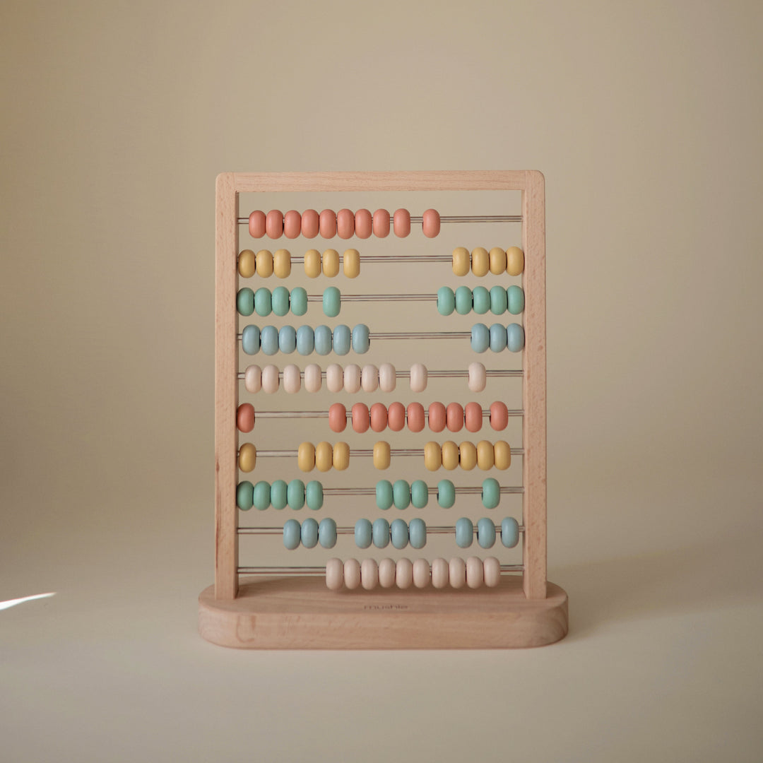 Toddler playing with the Mushie wooden abacus