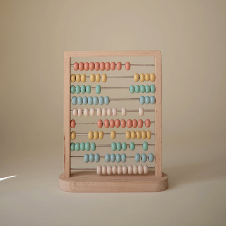 Toddler playing with the Mushie wooden abacus