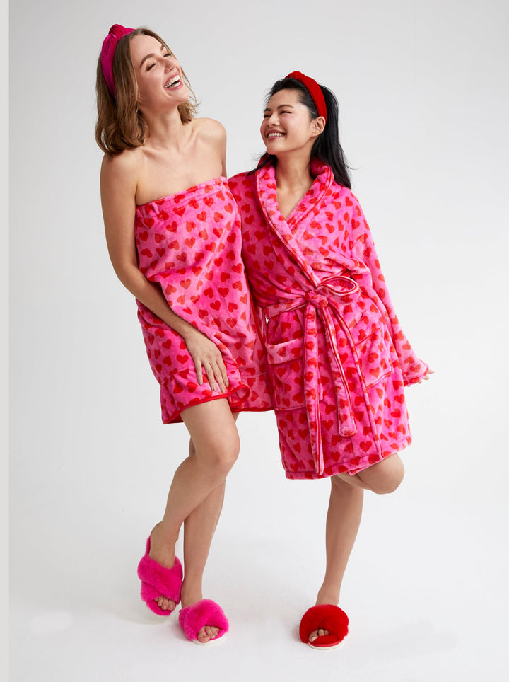 Two women wearing pink heart print bath wraps