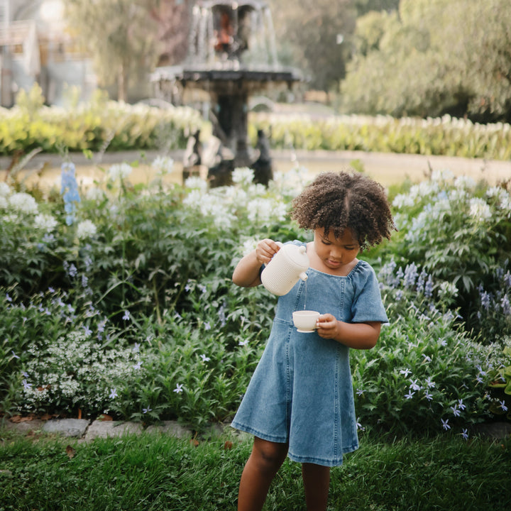 Girl playing with the Mushie silicone tea set
