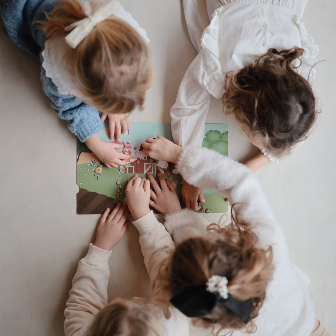 Child arranging puffy stickers in a Mushie reusable sticker book
