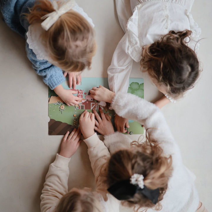 Child arranging puffy stickers in a Mushie reusable sticker book