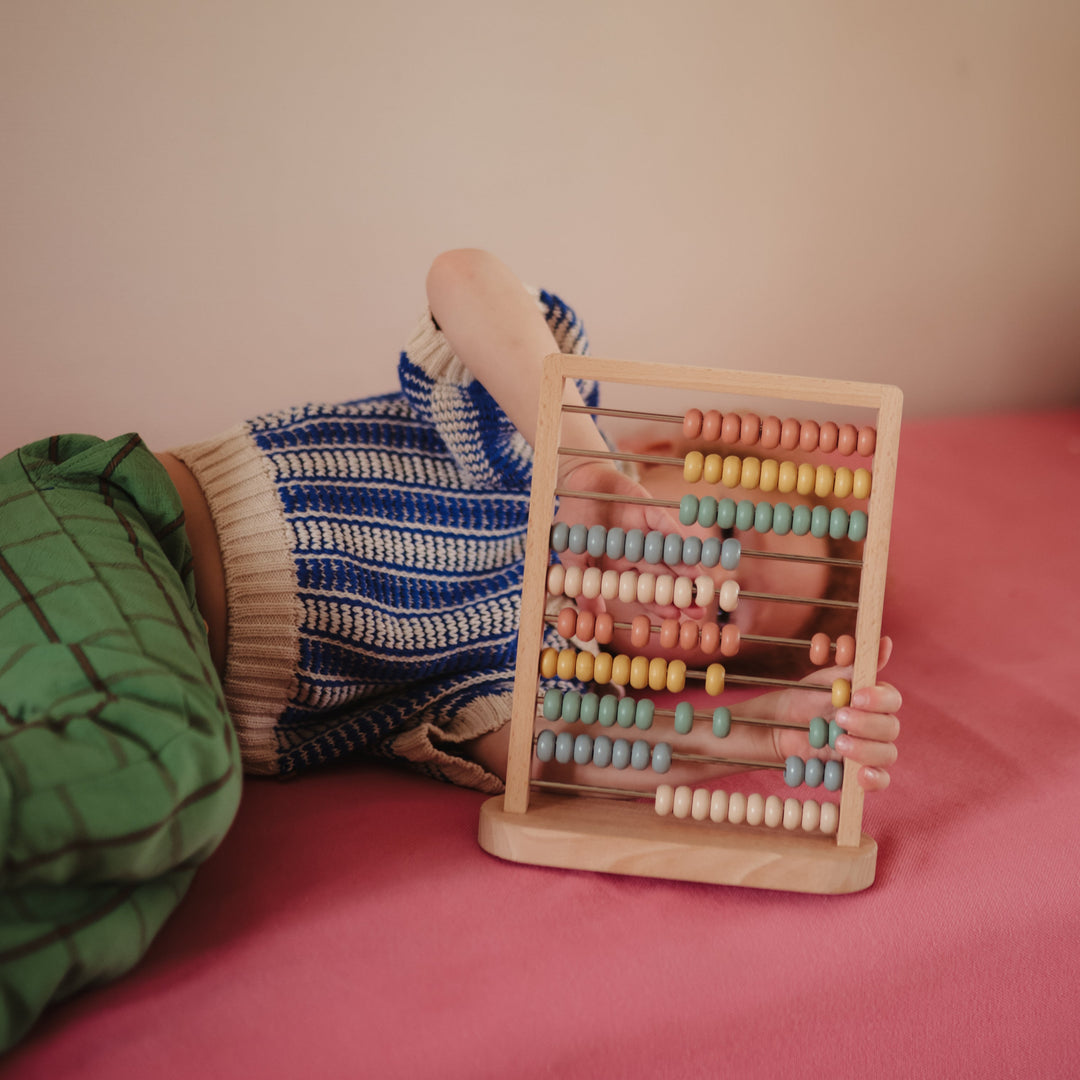 Child playing with the Mushie wooden abacus
