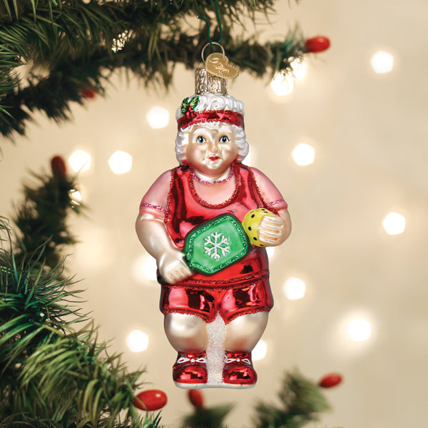 Mrs. Claus pickleball glass ornament in a red sweatband hanging on a lit Christmas tree