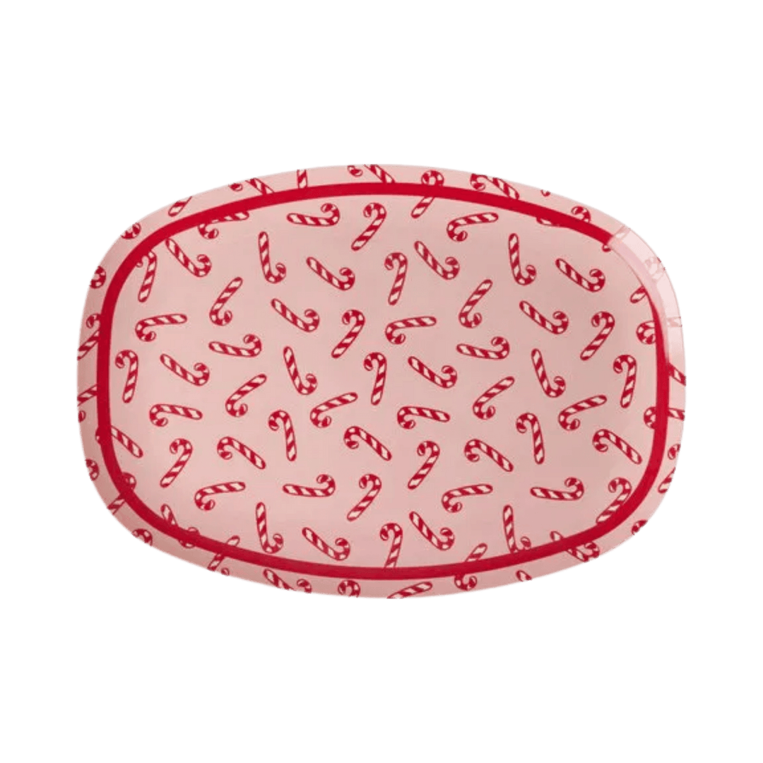 Rectangular pink melamine plate with red and white candy cane print and a red rim, top view on white