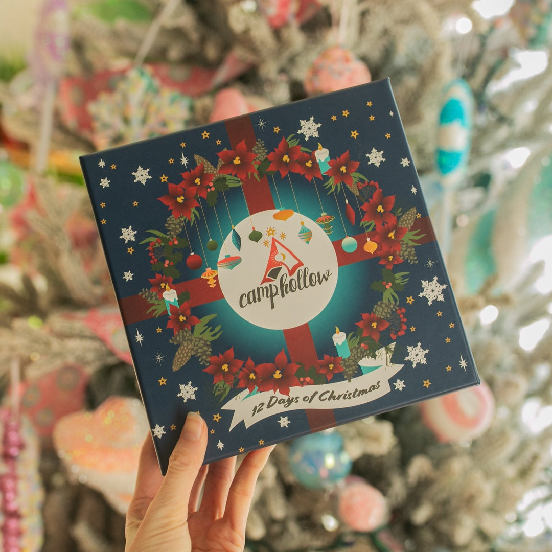 Hand holding the 12 Days of Christmas advent box with a wreath, red ribbon, and snowflakes