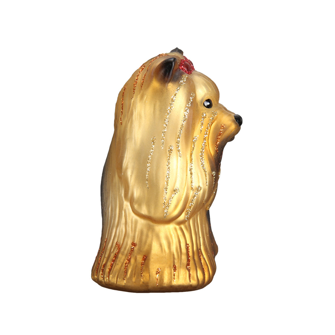 Yorkie ornament seen end-on, showing its red bow and flowing tan coat