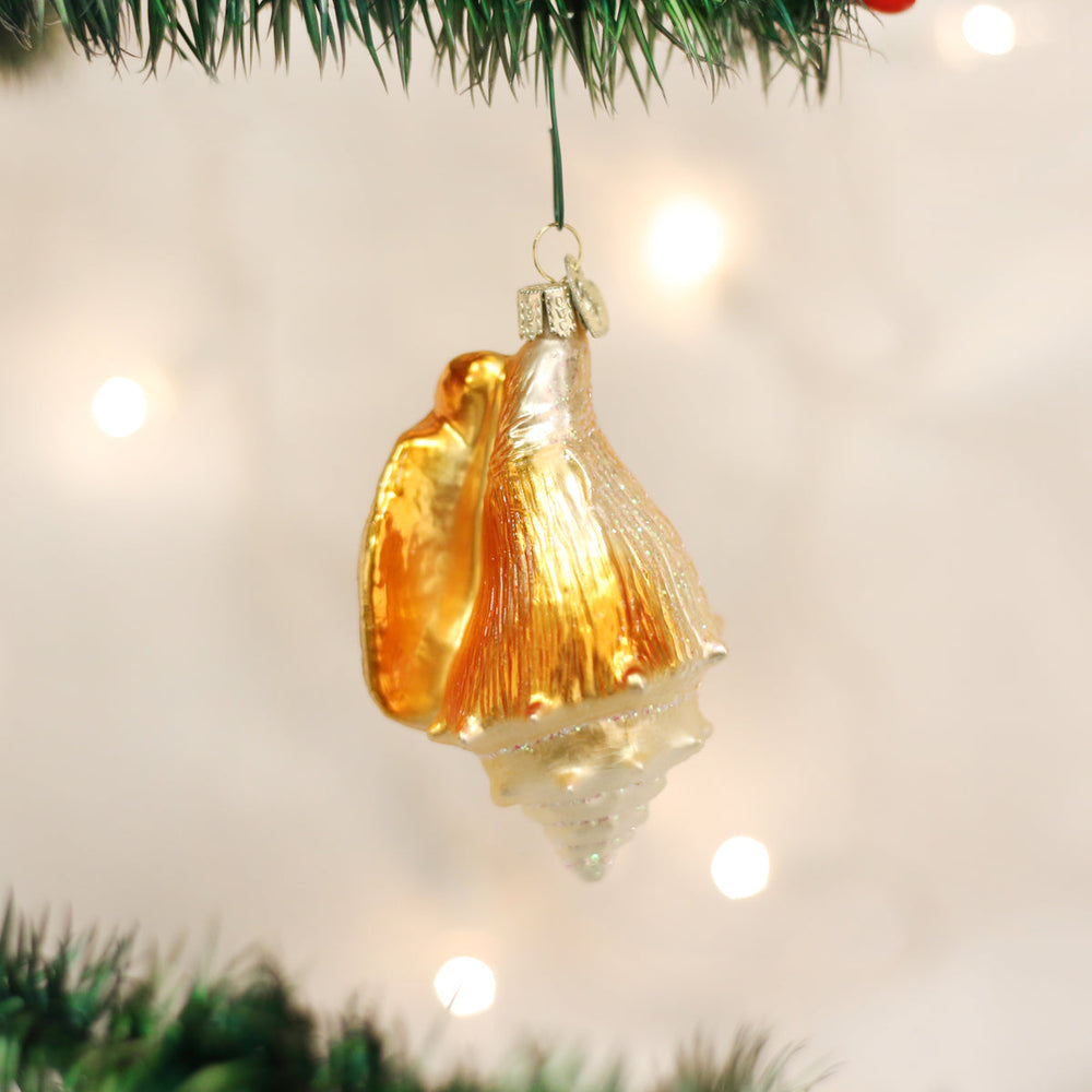 Golden seashell ornament hanging on a lit Christmas tree with warm bokeh lights