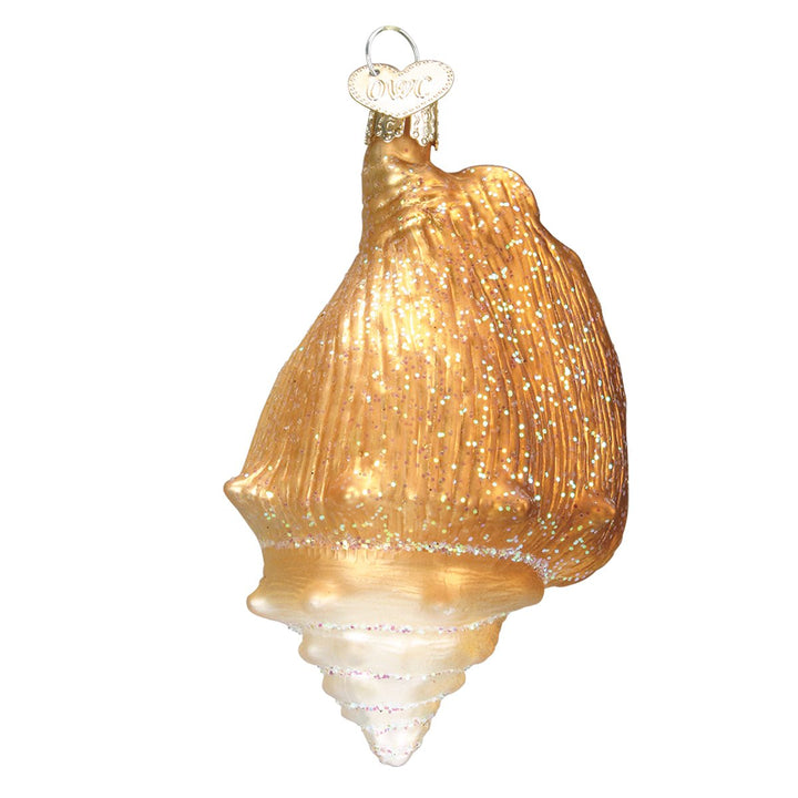Front of the amber gold glitter seashell glass ornament with a pearly spiral tip, on white