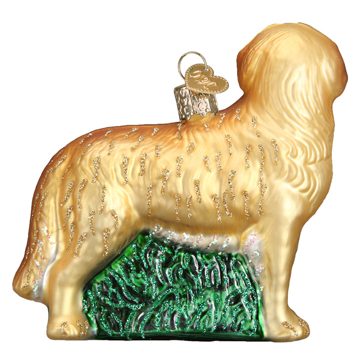 Back side view of the golden retriever ornament showing its feathered gold tail and green grass base
