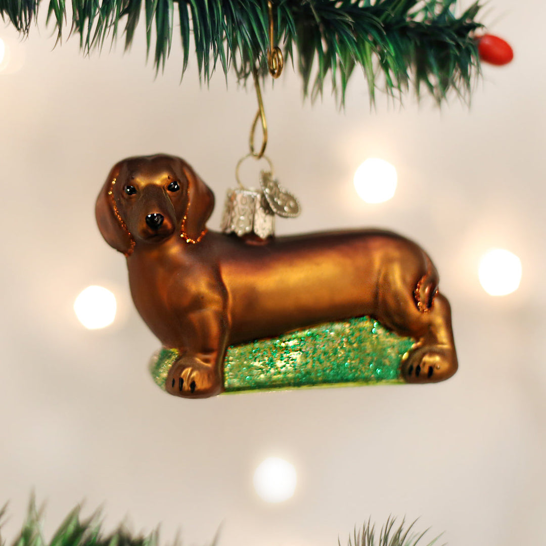 Dachshund glass ornament hanging on a Christmas tree with twinkling lights
