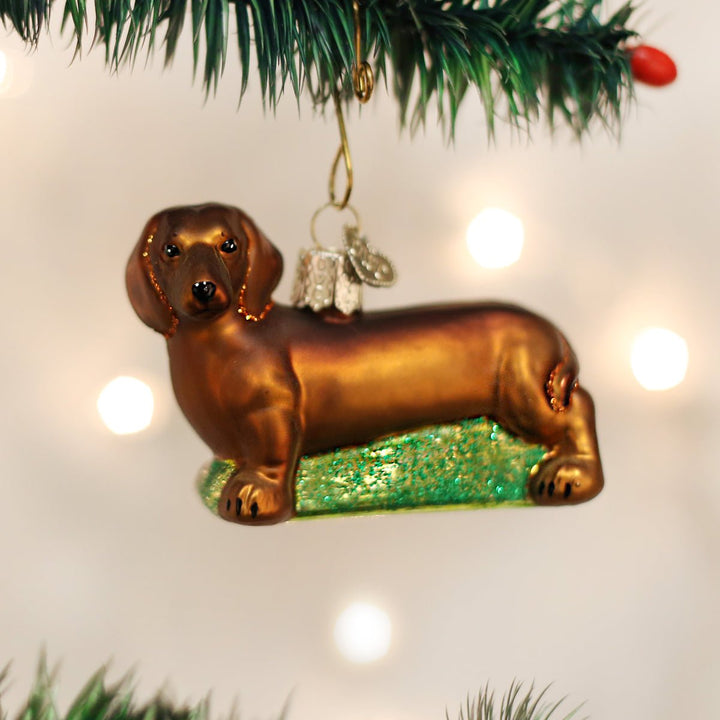 Dachshund glass ornament hanging on a Christmas tree with twinkling lights
