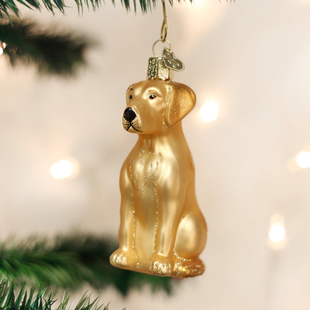 Yellow lab glass ornament hanging on a Christmas tree with warm bokeh lights