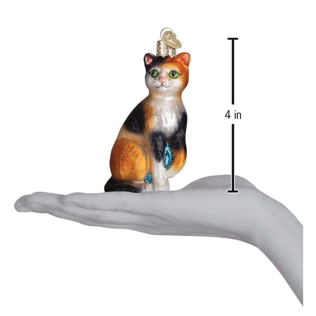 Calico cat ornament on an open palm with a 4 inch height marker for scale