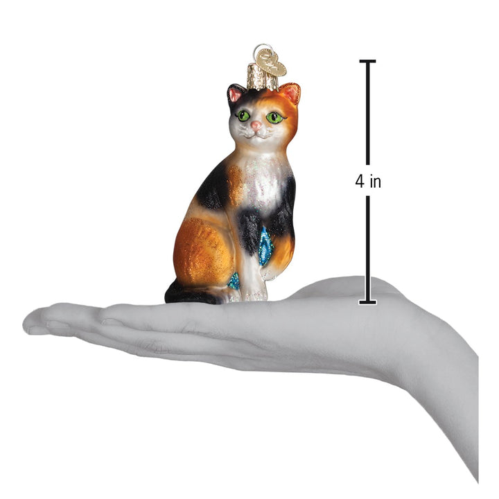 Calico cat ornament on an open palm with a 4 inch height marker for scale