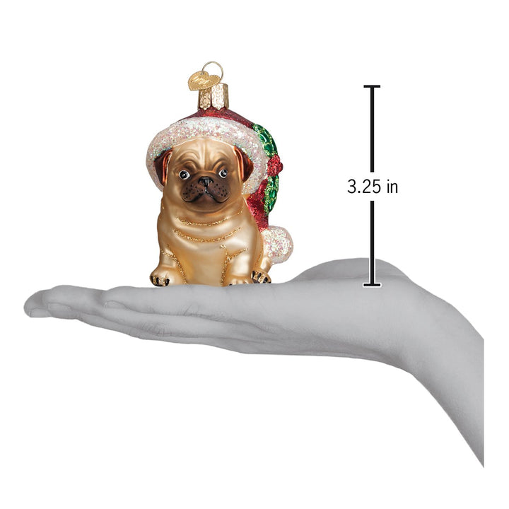 Holly hat pug ornament on an open palm with a 3.25 inch height marker for scale