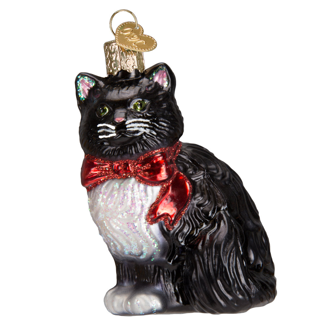 Tuxedo cat glass ornament, front view, black fur with white bib, green eyes, and a red glitter bow, on white
