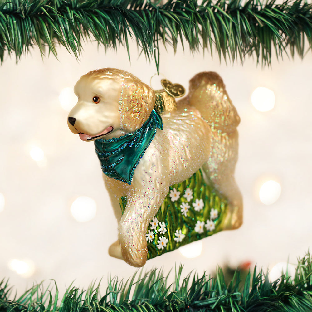 Doodle dog glass ornament hanging on a twinkling Christmas tree with pine garland