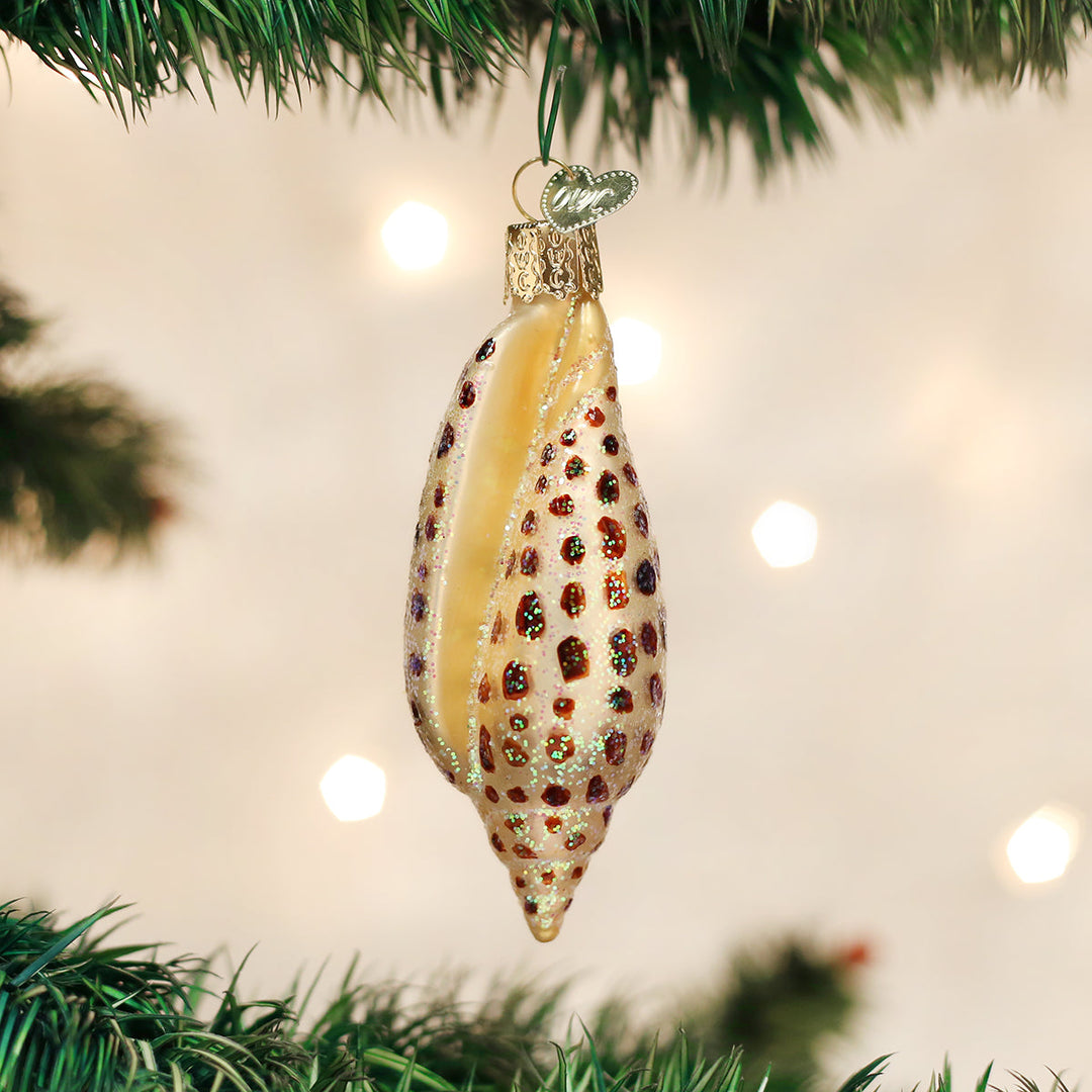 Junonia shell ornament hanging on a lit Christmas tree with warm bokeh lights