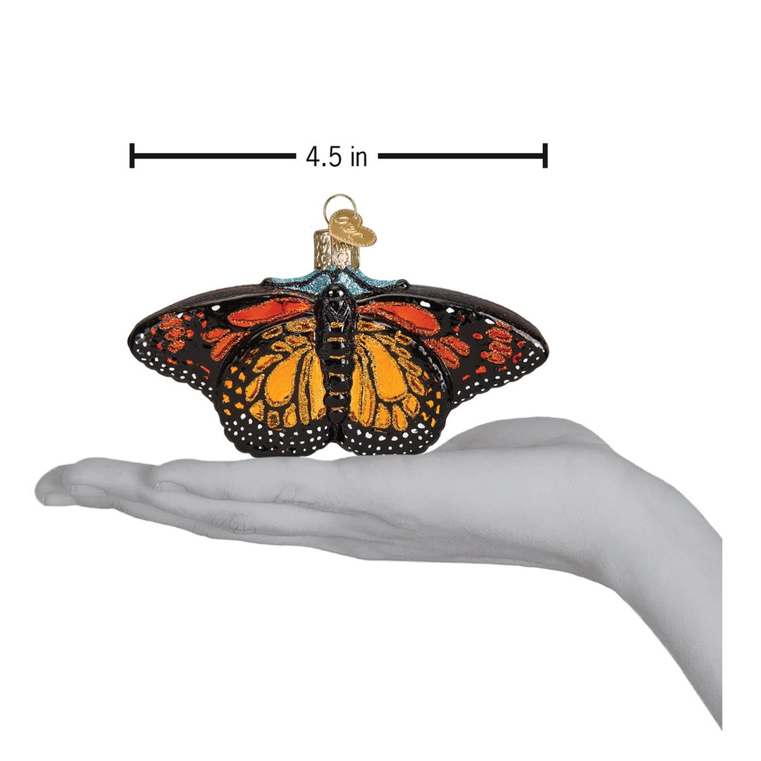Monarch butterfly ornament on an open palm with a 4.5 inch wingspan marker for scale