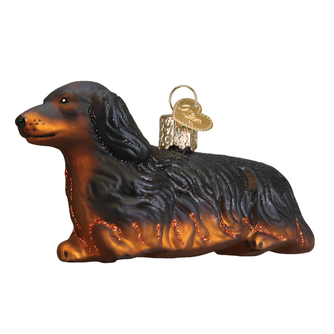 Black and tan long haired dachshund ornament lying down in glossy glass, side view