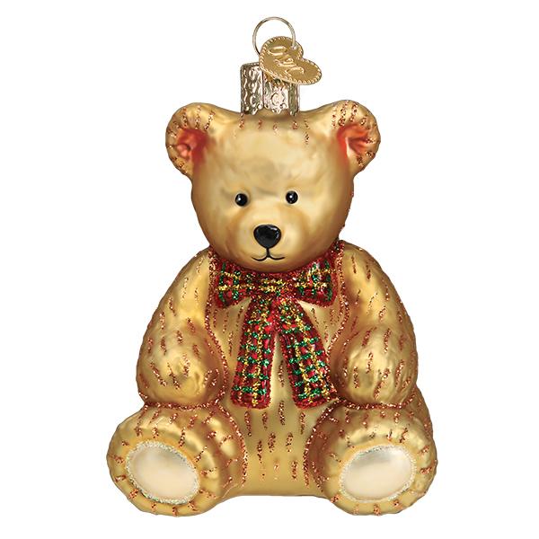 Front of the golden teddy bear ornament sitting with a red and green plaid bow, on white