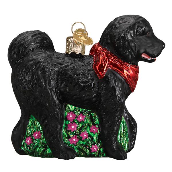 Black doodle dog ornament in a red bandana standing on green grass with pink flowers, side view