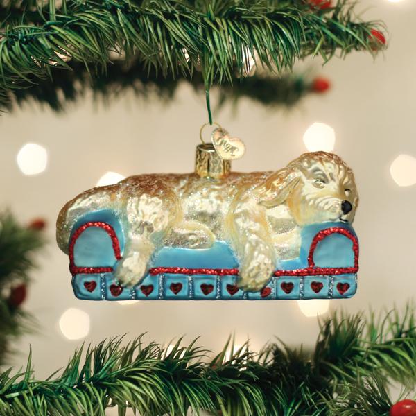 Sleepy doodle ornament hanging between pine branches on a twinkling Christmas tree