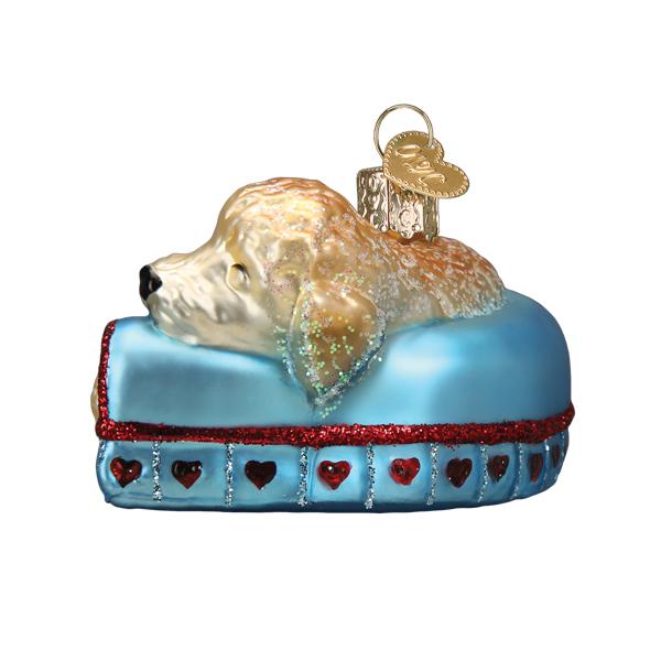 Angled view of the sleepy doodle ornament showing the dog's resting face on the blue couch arm
