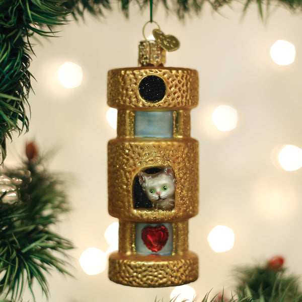 Cat tower ornament hanging on a Christmas tree with warm bokeh lights behind it